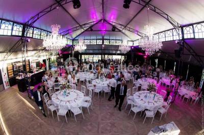 Commode rouge surmontée de cadres, lampe noire et carafe, avec un mur en pierre en arrière-plan.