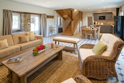 Commode rouge surmontée de cadres, lampe noire et carafe, avec un mur en pierre en arrière-plan.