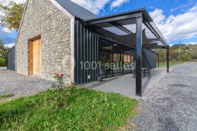 Une femme en robe de mariée sourit face à un homme en costume orange dans un vignoble verdoyant.