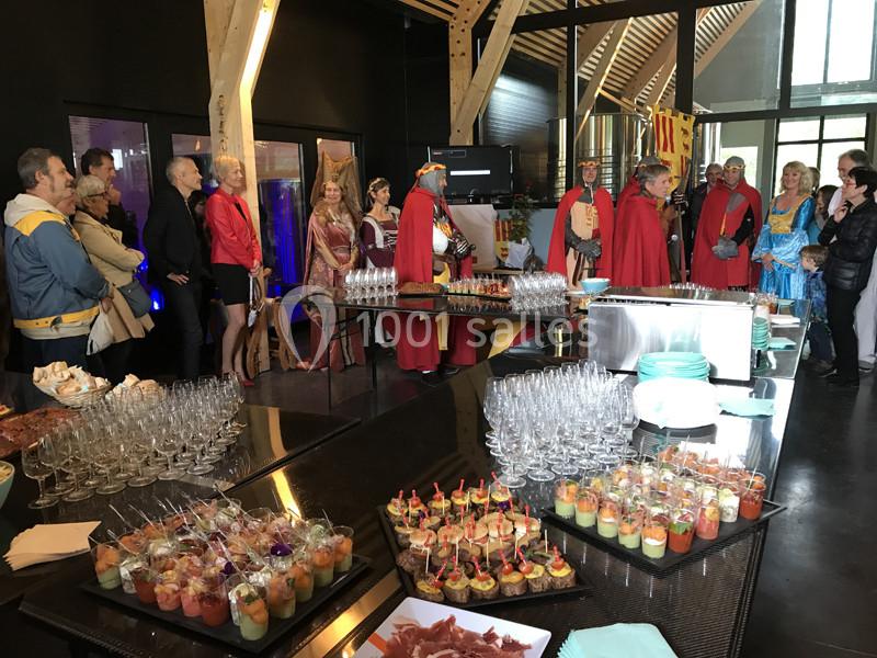 Personnes en tenue médiévale réunies autour d'une table garnie de verrines et amuse-bouches dans une salle moderne.