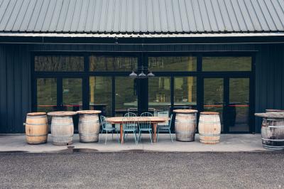 Une femme en robe de mariée sourit face à un homme en costume orange dans un vignoble verdoyant.