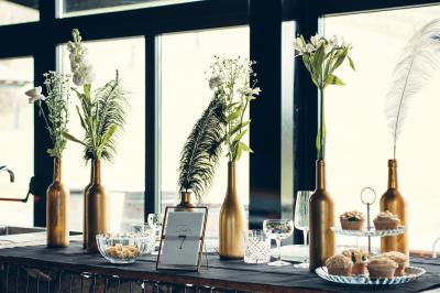 Une femme en robe de mariée sourit face à un homme en costume orange dans un vignoble verdoyant.