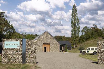 Une femme en robe de mariée sourit face à un homme en costume orange dans un vignoble verdoyant.