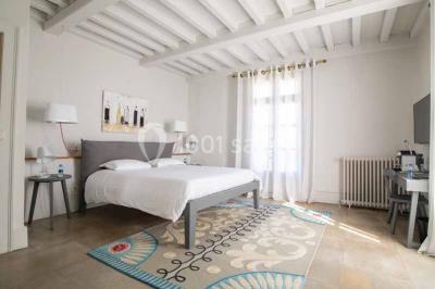 Façade d'une maison en pierre avec toit en tuiles, entourée de végétation dense sous une lumière douce.