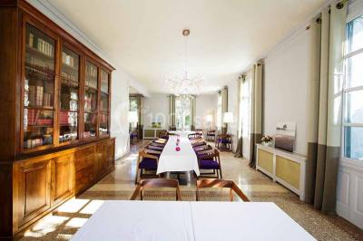 Façade d'une maison en pierre avec toit en tuiles, entourée de végétation dense sous une lumière douce.