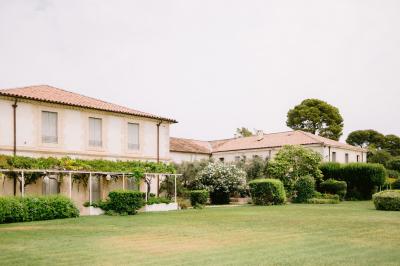 Façade d'une maison en pierre avec toit en tuiles, entourée de végétation dense sous une lumière douce.
