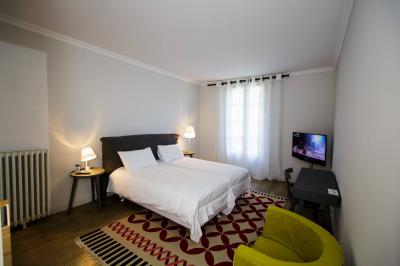 Façade d'une maison en pierre avec toit en tuiles, entourée de végétation dense sous une lumière douce.