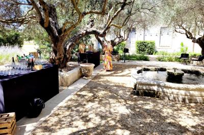 Façade d'une maison en pierre avec toit en tuiles, entourée de végétation dense sous une lumière douce.