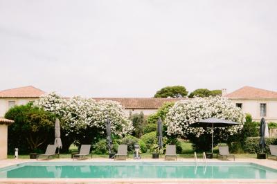 Façade d'une maison en pierre avec toit en tuiles, entourée de végétation dense sous une lumière douce.