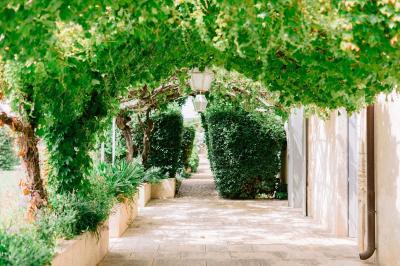 Façade d'une maison en pierre avec toit en tuiles, entourée de végétation dense sous une lumière douce.