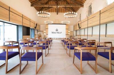 Façade d'une maison en pierre avec toit en tuiles, entourée de végétation dense sous une lumière douce.