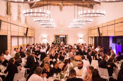 Façade d'une maison en pierre avec toit en tuiles, entourée de végétation dense sous une lumière douce.