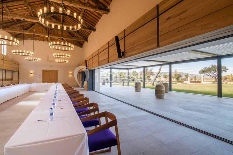 Salle de réunion lumineuse avec de grandes baies vitrées ouvertes sur un espace extérieur verdoyant.