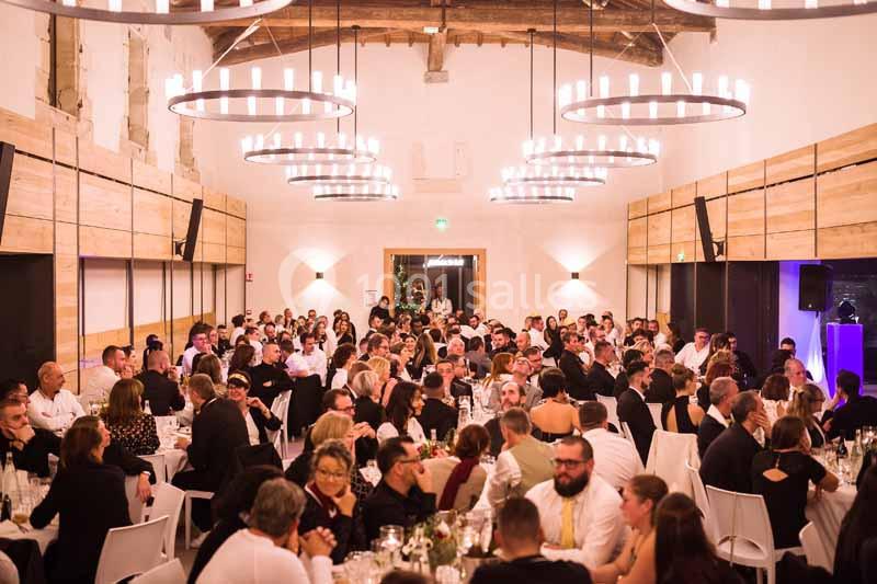Salle de réception lumineuse avec de nombreux convives assis à des tables lors d'un événement festif.