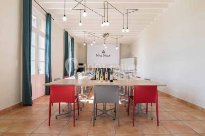 Façade d'une maison en pierre avec toit en tuiles, entourée de végétation dense sous une lumière douce.