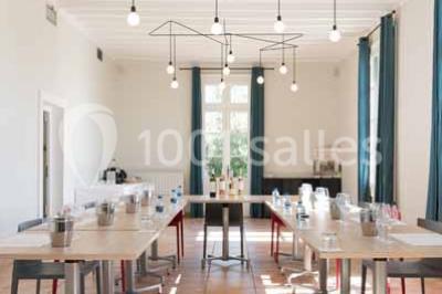 Façade d'une maison en pierre avec toit en tuiles, entourée de végétation dense sous une lumière douce.