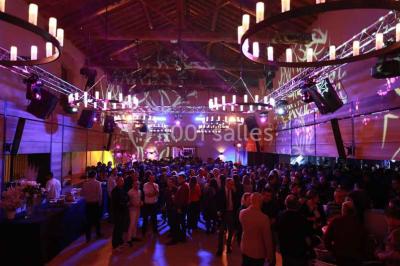 Façade d'une maison en pierre avec toit en tuiles, entourée de végétation dense sous une lumière douce.