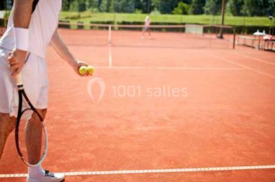 Façade d'une maison en pierre avec toit en tuiles, entourée de végétation dense sous une lumière douce.
