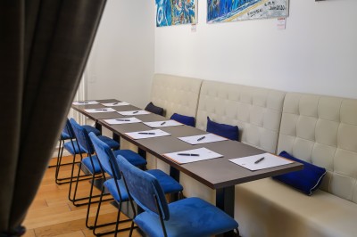 Chambre lumineuse avec lit double, canapé, fauteuils, table ronde et décoration murale dans un intérieur aux tons jaunes.