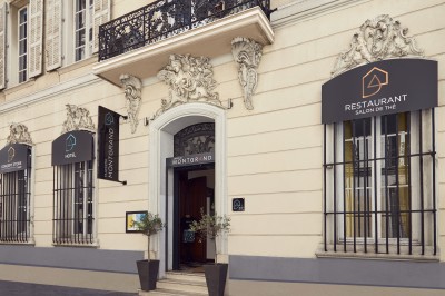 Chambre lumineuse avec lit double, canapé, fauteuils, table ronde et décoration murale dans un intérieur aux tons jaunes.