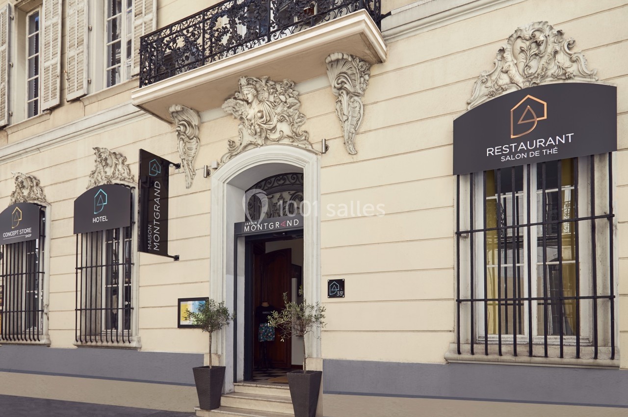 Façade d'un bâtiment avec entrée principale, enseignes d'hôtel et restaurant, et décorations architecturales.