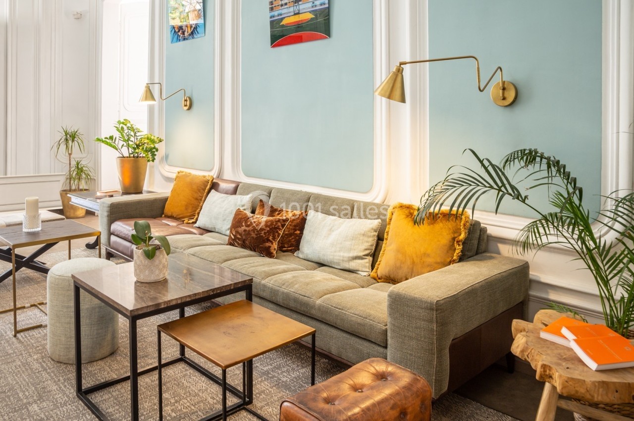 Salon lumineux avec canapé beige, coussins colorés, tables basses en bois et plantes décoratives.