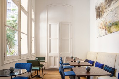 Chambre lumineuse avec lit double, canapé, fauteuils, table ronde et décoration murale dans un intérieur aux tons jaunes.