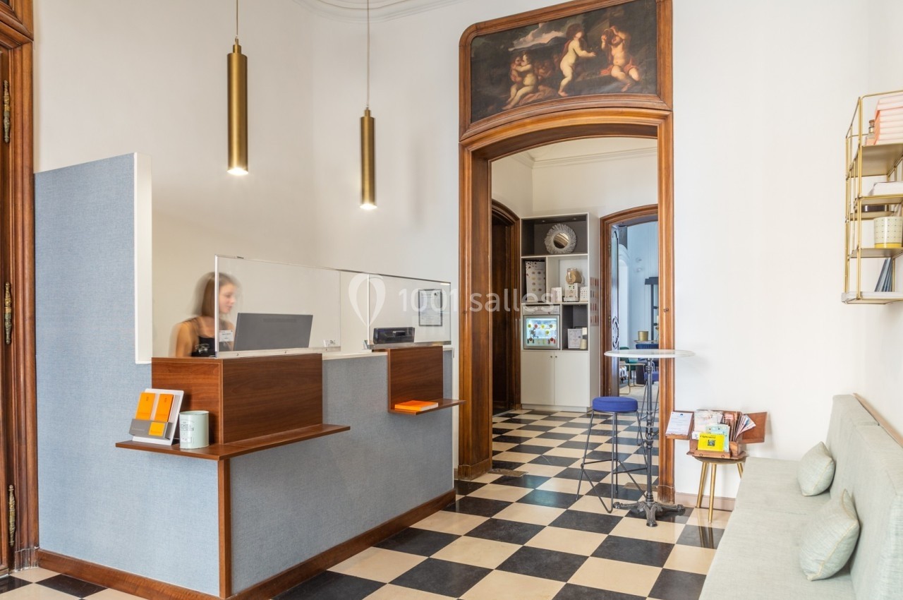 Accueil d'un espace professionnel avec comptoir en bois, sol en damier, et décoration murale classique.