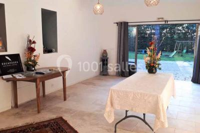 Salle décorée pour un événement, avec des tables alignées, nappes blanches, chemins de table rouges et lanternes suspendues.