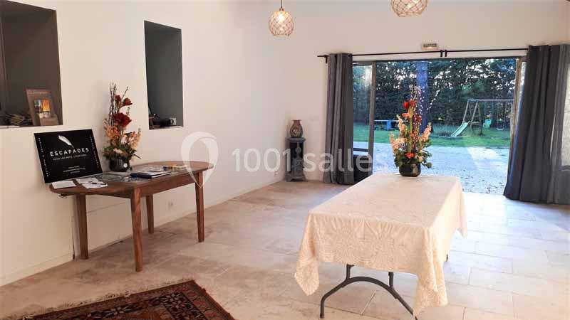 Salle lumineuse avec table recouverte d'une nappe, décorations florales et vue sur un jardin avec balançoire.
