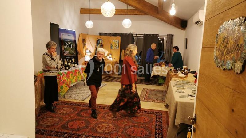 Des personnes discutent et se déplacent dans une pièce chaleureuse décorée pour un événement avec des tables dressées.
