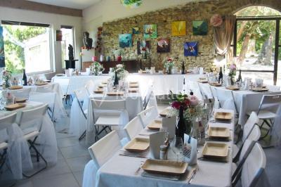 Salle décorée pour un événement, avec des tables alignées, nappes blanches, chemins de table rouges et lanternes suspendues.