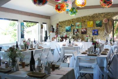 Salle décorée pour un événement, avec des tables alignées, nappes blanches, chemins de table rouges et lanternes suspendues.