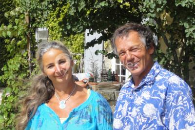 Salle décorée pour un événement, avec des tables alignées, nappes blanches, chemins de table rouges et lanternes suspendues.