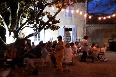 Salle décorée pour un événement, avec des tables alignées, nappes blanches, chemins de table rouges et lanternes suspendues.