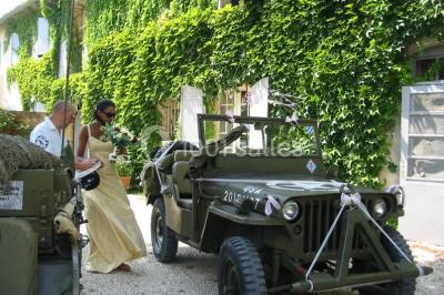 Salle décorée pour un événement, avec des tables alignées, nappes blanches, chemins de table rouges et lanternes suspendues.