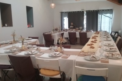 Salle décorée pour un événement, avec des tables alignées, nappes blanches, chemins de table rouges et lanternes suspendues.