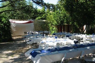 Salle décorée pour un événement, avec des tables alignées, nappes blanches, chemins de table rouges et lanternes suspendues.