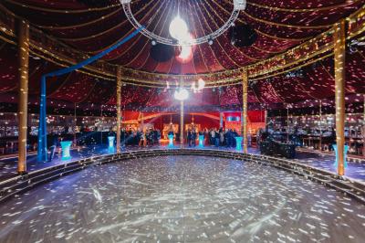 Miniature Cabaret Sauvage - Soirée dansante Terrasse extérieure avec tables rondes, chaises pliantes et guirlandes lumineuses suspendues, ambiance en soirée.