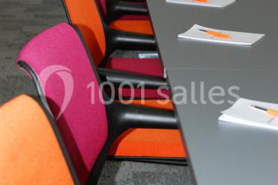 Salle lumineuse avec décoration naturelle, comprenant un canapé en bois, une table en tronc d'arbre et des chaises colorées.