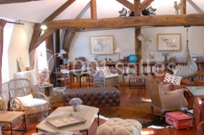 Salle lumineuse avec décoration naturelle, comprenant un canapé en bois, une table en tronc d'arbre et des chaises colorées.