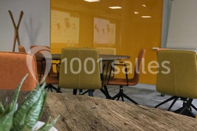 Salle lumineuse avec décoration naturelle, comprenant un canapé en bois, une table en tronc d'arbre et des chaises colorées.