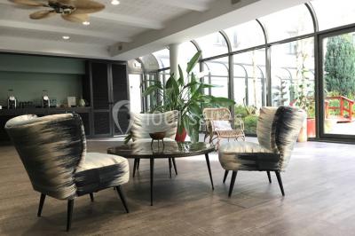 Salle lumineuse avec décoration naturelle, comprenant un canapé en bois, une table en tronc d'arbre et des chaises colorées.