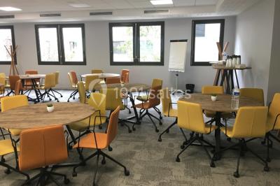 Salle lumineuse avec décoration naturelle, comprenant un canapé en bois, une table en tronc d'arbre et des chaises colorées.