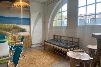 Salle lumineuse avec décoration naturelle, comprenant un canapé en bois, une table en tronc d'arbre et des chaises colorées.