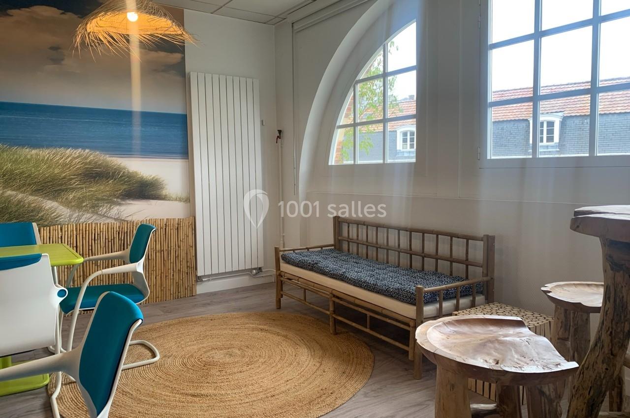Salle lumineuse avec décoration naturelle, comprenant un canapé en bois, une table en tronc d'arbre et des chaises colorées.