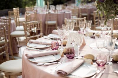 Bouquet de roses roses posé sur une surface blanche avec deux alliances dorées au premier plan.