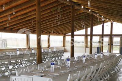 Maison blanche aux volets bleus éclairée la nuit, entourée d'arbres et d'une pelouse.