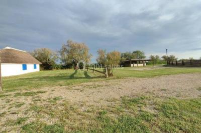 Maison blanche aux volets bleus éclairée la nuit, entourée d'arbres et d'une pelouse.
