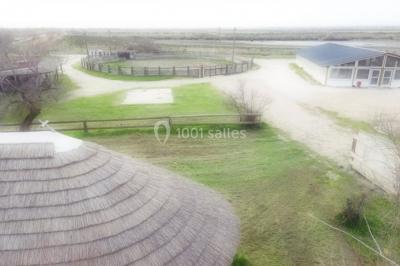 Maison blanche aux volets bleus éclairée la nuit, entourée d'arbres et d'une pelouse.